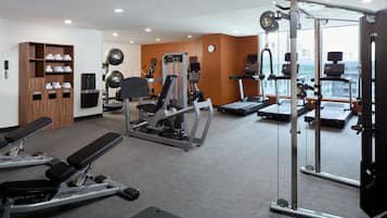 Et fitnessrum med forskellig træningsudstyr, et løbebånd og en vægtmaskine.