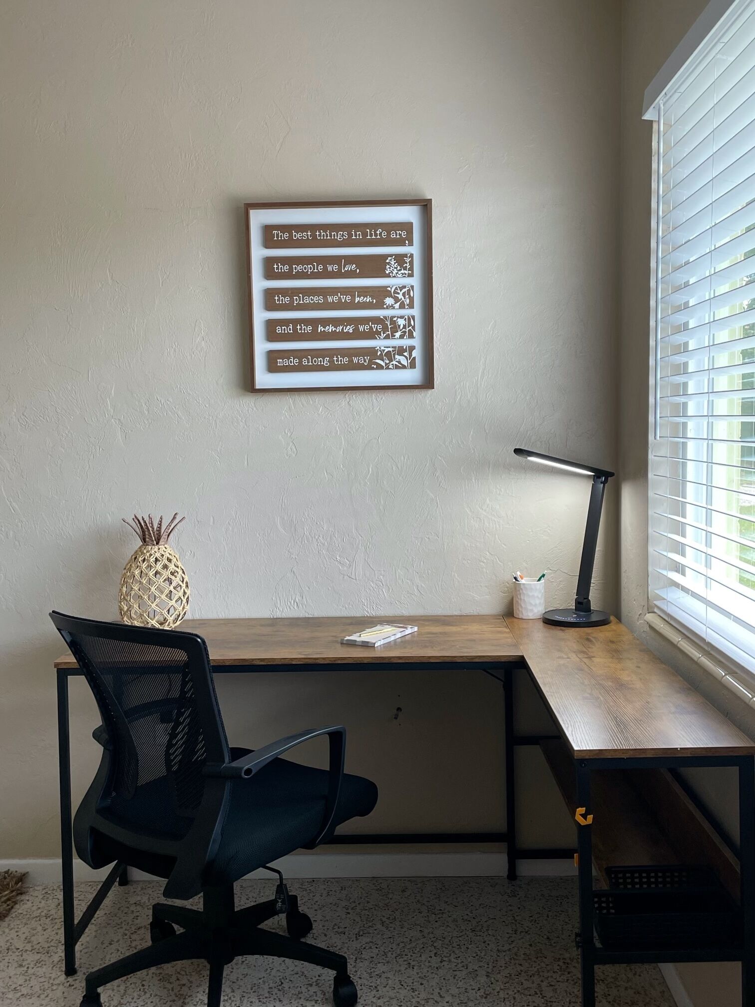 Un espacio de trabajo con escritorio, silla y una cita inspiradora enmarcada en la pared.