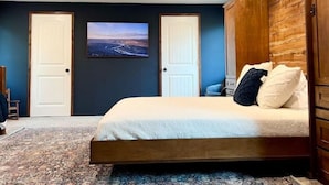 Een slaapkamer met een bed, een plafondventilator, twee deuren en een lijst met een afbeelding aan de muur.