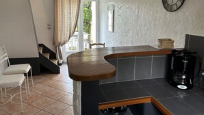 Une cuisine avec un plan de travail en bois, une machine à café et une horloge au mur.