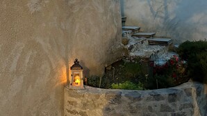 Un mur de pierre, une lanterne et un petit jardin agrémenté de fleurs et de plantes.