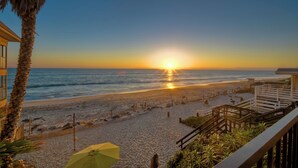 Scena di spiaggia con un tramonto, una palma e un ombrellone giallo.