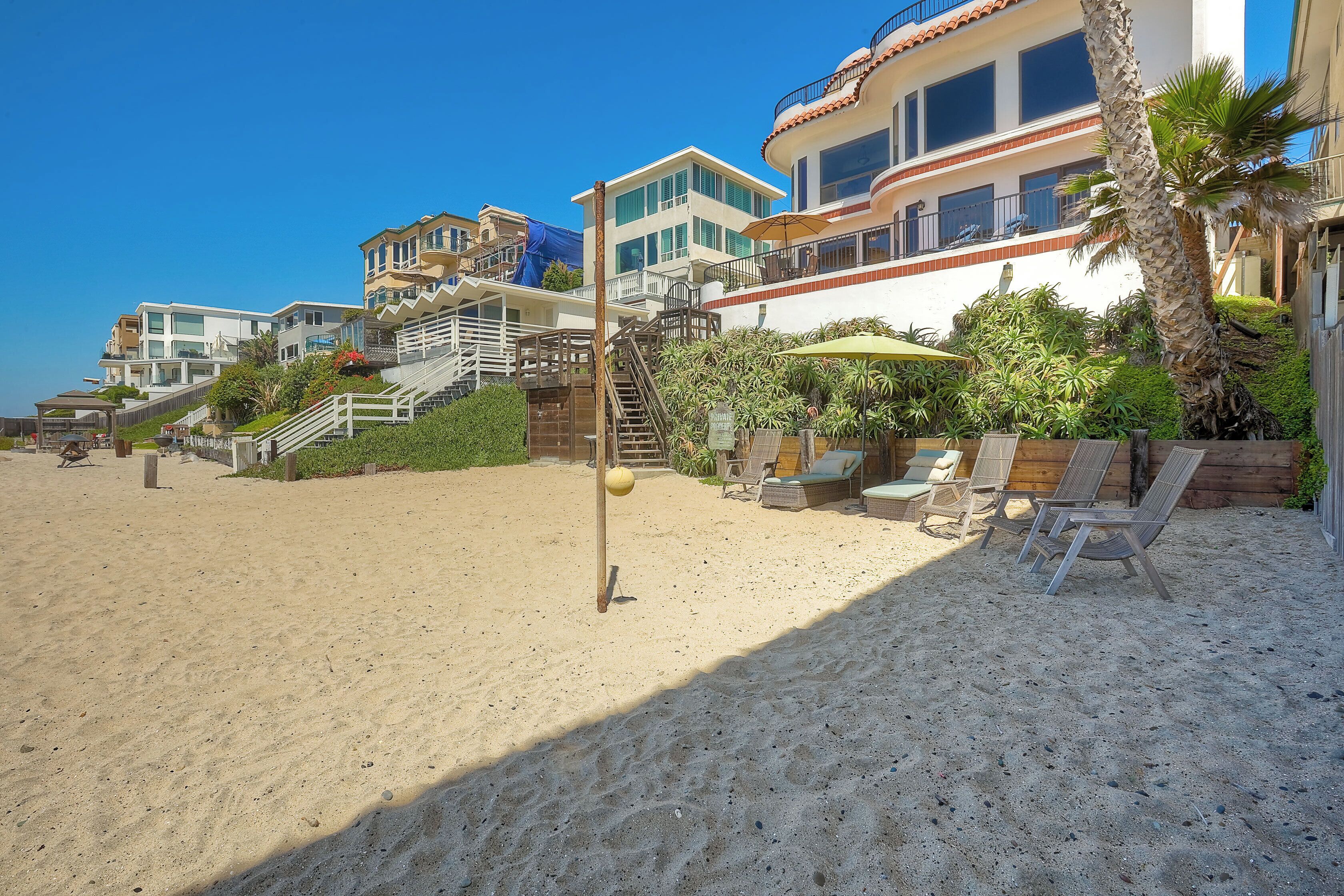 A beachfront property with multiple buildings, a sandy beach, and outdoor seating areas.