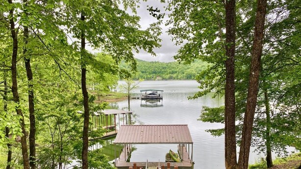 A wooden dock leading to a small wooden pier with a covered seating area overlooking a calm lake. - Lakefront Cottage with Private Dock on Norris Lake (Sharps Chapel)