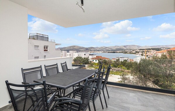 A balcony with a table and chairs, overlooking a coastal town and a body of water. - Nice apartment in Okrug Gornji with WiFi (Okrug Gornji)