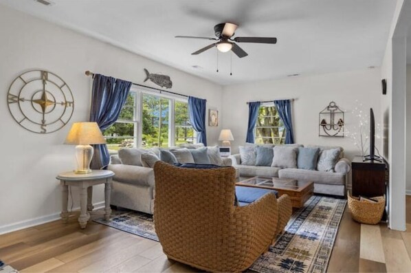 A living room with a sofa set, a woven chair, a coffee table, and a ceiling fan. - Reel Nice Home (Beaufort)