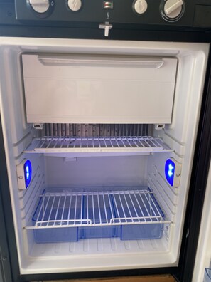 Tyhjä jääkaappi, jossa on kaksi hyllyä ja pakastelokero.