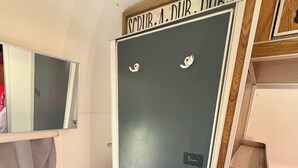 Pieni kylpyhuone, jossa on pesuallas, peili ja ovi, jossa lukee: ”SCURR.A. DNR.”
