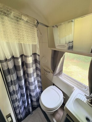 A compact bathroom with a toilet, sink, and shower area.
