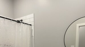 Une salle de bain équipée de toilettes, d’un lavabo, d’un rideau de douche et d’un miroir.