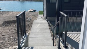Un camino de hormigón que lleva a un edificio con vistas a un lago y montañas.