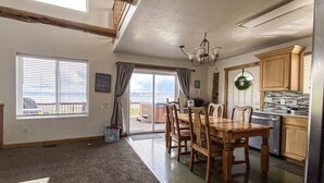 A spacious living area with a dining table, wooden chairs, a chandelier, and a view to the outside. - Raspberry Patch View- New Listing with new hot tub (Garden City)