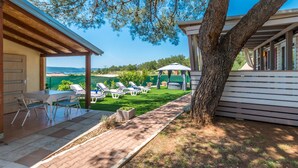 Un patio con mobiliario exterior, una zona cubierta y vista al mar.