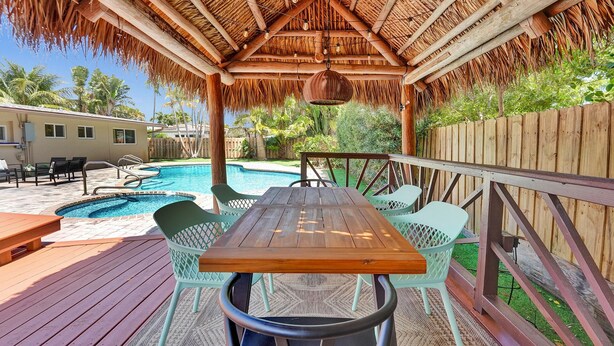 Un espace extérieur abrité, avec une table et des chaises en bois, une piscine et une clôture en bois.