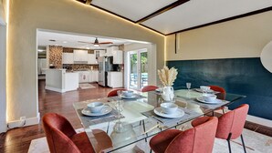 Un espace repas moderne avec une table en verre pour quatre personnes, entourée de chaises rouges.