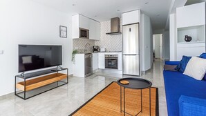 Ein modernes Wohnzimmer mit Fernseher, Sofa und einem kleinen Tisch.