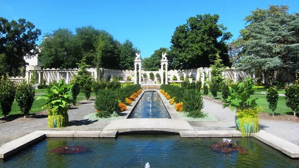 A formal garden with a central water feature, symmetrical pathways, and statues. - Luxury Living in the Heart of NY (Yonkers)