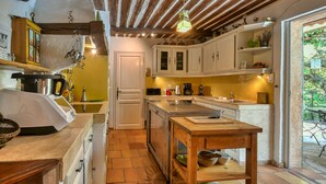 A kitchen with white cabinets, a wooden table, and a hanging light fixture. - SERENITY Villa for 8 By Sunset (Grasse)