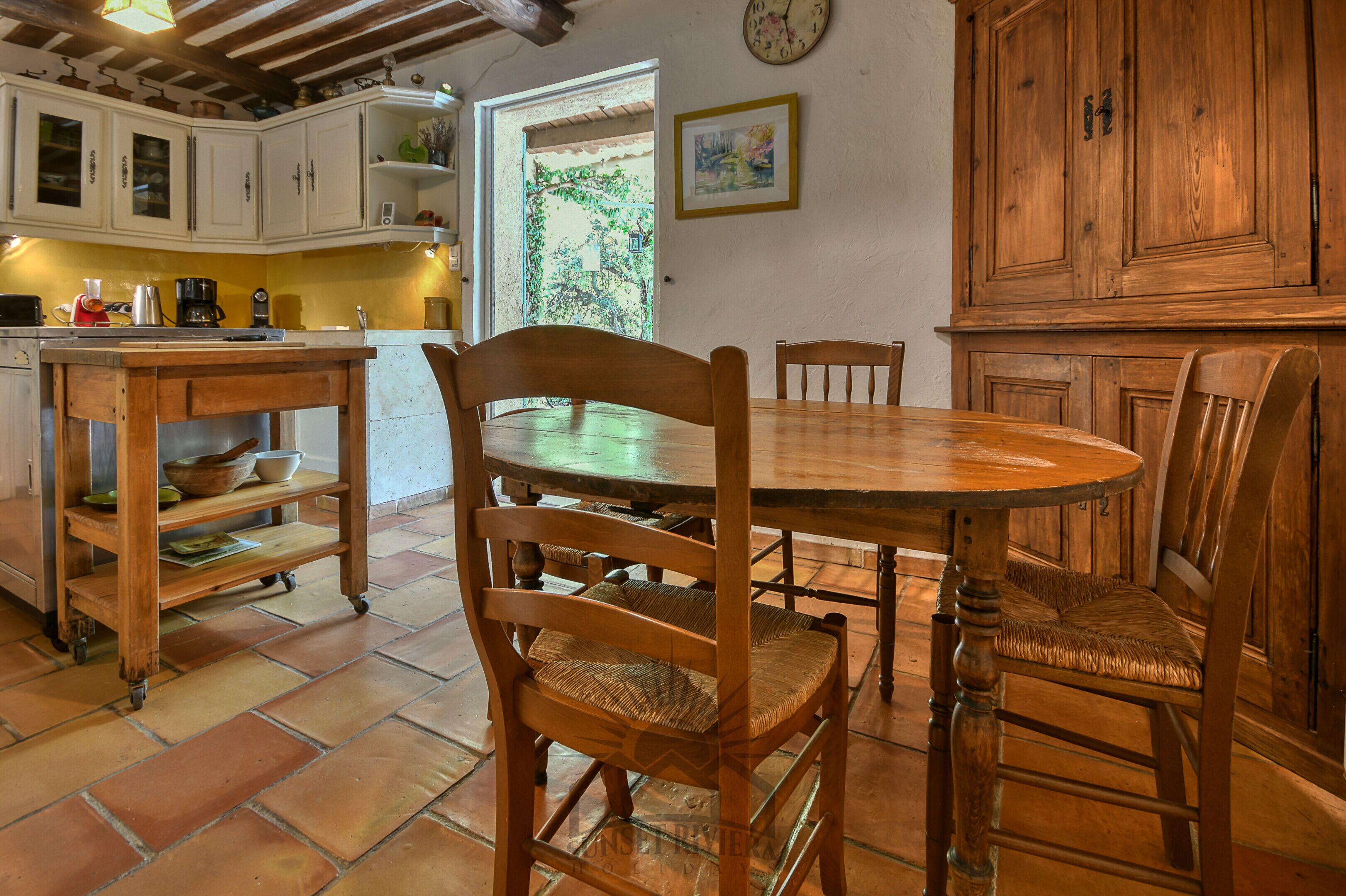 A rustic kitchen with wooden cabinets, a dining table, and chairs.