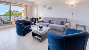 A modern living room with a sofa, two armchairs, a coffee table, and a dining area. - LA BADINE Appartement AirCo Pool for 4 By Sunset (Antibes)