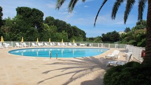 A swimming pool with lounge chairs and a white fence. - LA BADINE Appartement AirCo Pool for 4 By Sunset (Antibes)