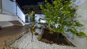 Un jardín en la azotea con guijarros blancos, una valla de madera y un árbol de hojas verdes.
