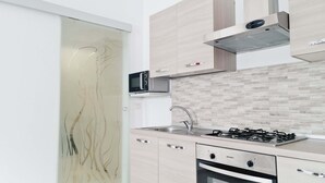 A modern kitchen with a gas stove, stainless steel sink, and a microwave.