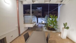 A modern dining area with a table and chairs, a small garden with plants, and a glass door leading to an outdoor balcony.