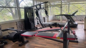 A gym with exercise equipment, large windows, and a view of trees.