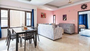 A living room with a sofa, a dining table with chairs, and a ceiling fan.