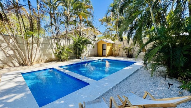 A rectangular swimming pool with two separate sections, surrounded by a white gravel area and tropical plants. - 5 Minute walk to the beach! (Guanacaste Province)
