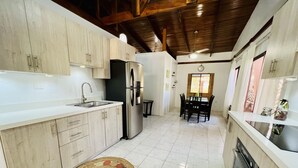 A kitchen with wooden cabinets, a stainless steel refrigerator, a sink, and a dining area with a table and chairs. - 5 Minute walk to the beach! (Guanacaste Province)