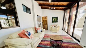 A spacious living room with a cream-colored sofa, a round coffee table, and a colorful rug. - 5 Minute walk to the beach! (Guanacaste Province)