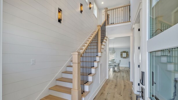 A staircase with wooden steps and black railings, leading to a second floor with a balcony. - Bright airy lakeside home in gated community (Winchester)