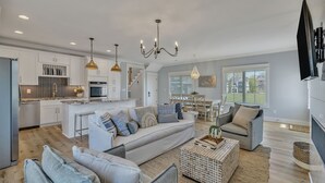 A modern kitchen with white cabinets, a central island, and pendant lighting. - Bright airy lakeside home in gated community (Winchester)