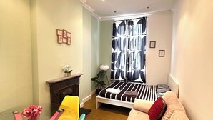 Een compacte slaapkamer met een bed, een bank, een klein tafeltje en een stoel.