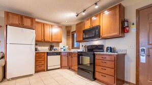 Eine Küche mit Holzausbau, einem weißen Kühlschrank, einer Mikrowelle, einem Backofen und einem Geschirrspüler.