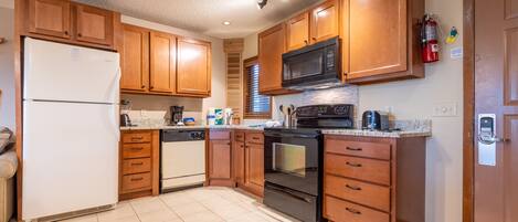 A kitchen with wooden cabinets, a white refrigerator, a microwave, an oven, and a dishwasher.