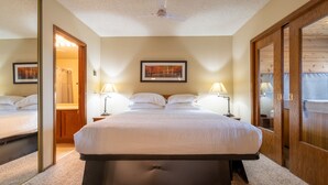 Ein Schlafzimmer mit Bett, Nachttischlampen, Deckenventilator und einem gerahmten Bild an der Wand.