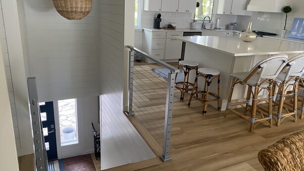 A modern kitchen with white cabinets, a wooden floor, and a bar area with stools. - Long Beach Cottage with Lake views and one block walk to Stop 26.   (Long Beach)