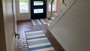 A hallway with a dark door, a striped rug, and a staircase. - Long Beach Cottage with Lake views and one block walk to Stop 26.   (Long Beach)
