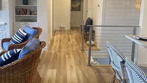 A hallway with a wicker chair, a bookshelf, and a dining area with a table and chairs. - Long Beach Cottage with Lake views and one block walk to Stop 26.   (Long Beach)
