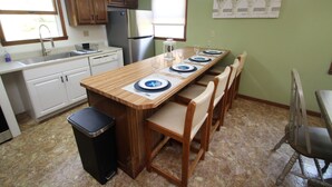 A kitchen with a wooden island, white cabinets, a stainless steel refrigerator, and a trash can. - Streamside Family Friendly Accommodations minutes from Ohiopyle! (Farmington)