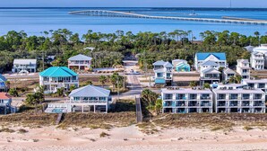 Une zone côtière dotée de propriétés en bord de mer, d’une jetée s’avançant dans l’eau et d’une plage à la végétation clairsemée.