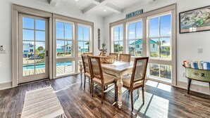 Un espace repas avec une grande table et des chaises, un tapis et un panneau indiquant : « Profitons du coucher de soleil ».