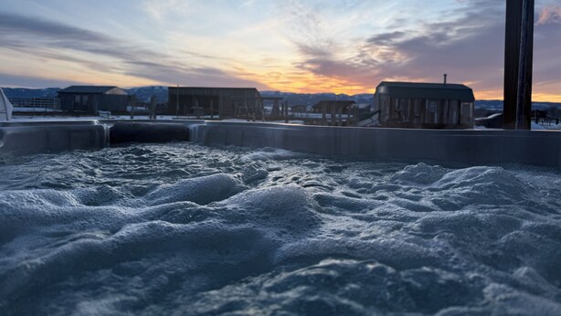 A hot tub with a view of a sunset and mountains in the background. - Private farm house lock off on sheep farm with salt hot tub (Driggs)