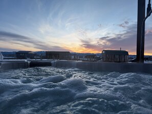 Un bain à remous avec vue sur un coucher de soleil et des montagnes en arrière-plan.