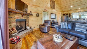 A cozy log cabin interior with a stone fireplace, leather recliner, and a dark leather sofa. - Mountain View & Fire Pit: Updated Murphy Cabin! (Murphy)
