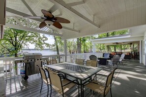 Un patio extérieur couvert, équipé d’un barbecue, d’une table, de chaises et d’un ventilateur de plafond.