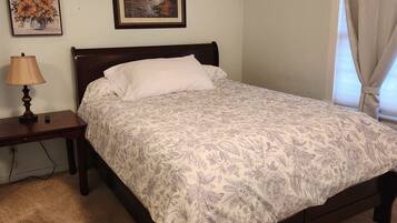 Una camera da letto con un letto, un comodino, una lampada e due quadri appesi al muro.